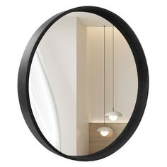 a round mirror hanging from the side of a white wall next to a light fixture