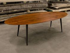 an oval wooden table with black legs in a warehouse