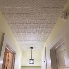 an empty hallway with white walls and ceiling tiles on the ceiling, along with two doors