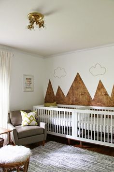 a baby's room with mountains painted on the wall and a crib in the corner