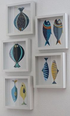 four framed pictures with fish on them hanging on the side of a wall in white frames