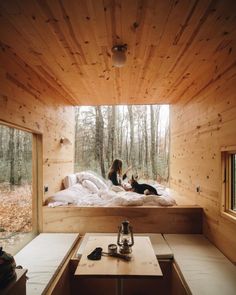 a woman sitting on top of a bed in a room filled with wood paneled walls