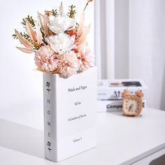 a vase filled with flowers sitting on top of a white table next to a clock