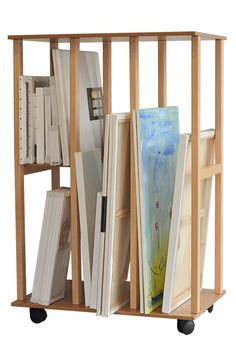 a wooden shelf filled with lots of books on wheels next to a white wall behind it