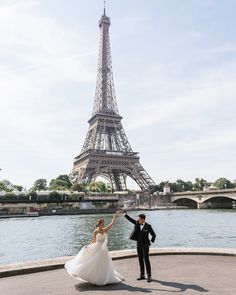 a bride and groom dancing in front of the eiffel tower