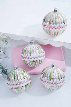 three ornaments are sitting on a pink box