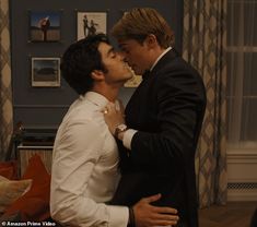 two men in suits are kissing each other while one man is wearing a white shirt and tie