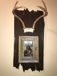 a deer's head mounted to the side of a wooden wall hanging on a wall