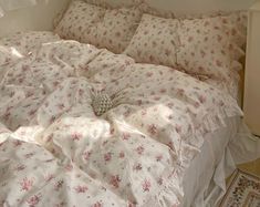 an unmade bed with white sheets and pink flowers