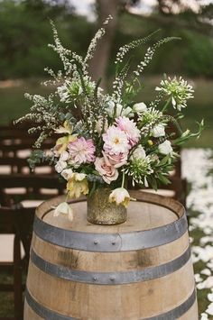 a vase filled with flowers sitting on top of a wooden barrel