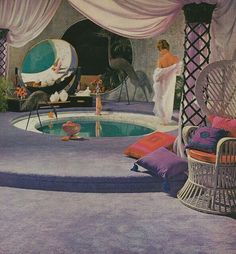 a woman in a white bathrobe standing next to a swimming pool and wicker chairs