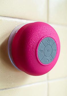 the bluetooth shower speaker is pink and has a round button on it's side