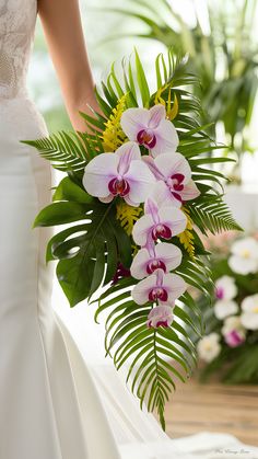 a bride holding a bouquet of orchids in her wedding dress and standing next to the groom