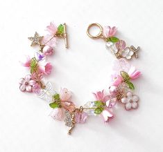 This delicate lily of the valley charm bracelet is handcrafted by myself.  The gold plated chain is 7 3/4 inches long with a toggle clasp.  It contains glass butterflies, a heart,  flowers and lots of crystals so it sparkles as you move.  If you need it shorter or longer just let me know, and I will adjust it to as close as possible to the size you desire.  Each charm is placed with thought  for color and balance.  It is  a really pretty bracelet, and sure to make you smile for years to come. If Elegant Handmade Flower Charm Bracelet, Fairycore Flower Jewelry For Gifts, Whimsical Gold Charm Bracelet, Crystal Bracelet Ideas, Lily Of The Valley Bracelet, Lily Of The Valley Fairy, Handmade Pink Fairy Jewelry, Fantasy Objects, Adjustable Flower-shaped Charm Bracelets