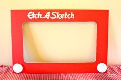 a red and white photo frame sitting on top of a checkered cloth covered table