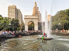 people are standing in the water near a fountain