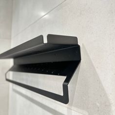 a black shelf mounted to the side of a white wall