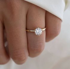 a woman's hand with a gold ring and a diamond on top of it