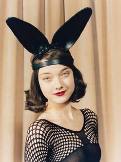 a woman with bunny ears on her head wearing a sheer top and black mesh dress