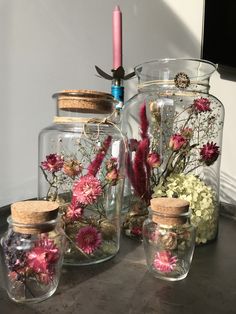 three glass jars with flowers in them sitting on a table