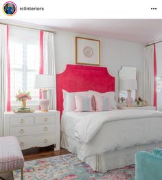 a white bed with pink headboard and pillows in a bright colored bedroom, along with two blue chairs