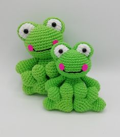 two green crocheted stuffed animals sitting next to each other