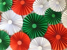 many red and green paper fans are arranged in a pattern on the wall behind them