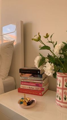 a vase filled with white flowers sitting on top of a table next to a stack of books