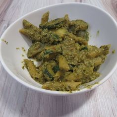 a white bowl filled with green food on top of a wooden table