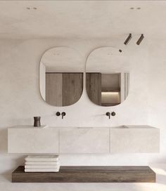 a bathroom with two sinks and mirrors on the wall next to each other in front of white walls