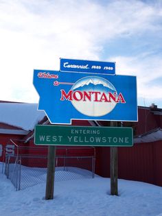 there is a sign that says montana and west yellowstone in front of a red building