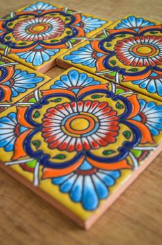 three colorful coasters sitting on top of a wooden table