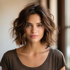 a close up of a person wearing a brown shirt and hair in front of a window