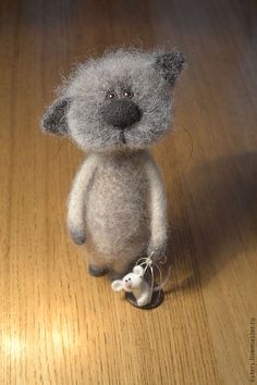 a gray stuffed animal sitting on top of a wooden floor next to a white mouse