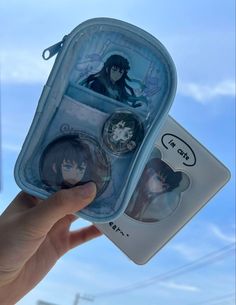 someone is holding up a plastic case with some anime pictures on it and two other items in front of them