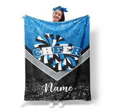 a woman is holding up a blue and black cheer blanket that says name on it