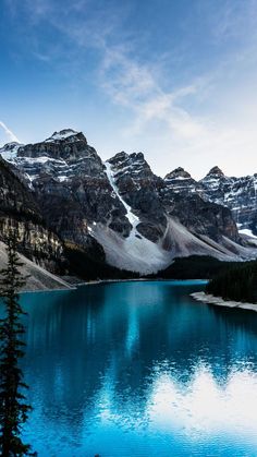 a lake surrounded by snow covered mountains under a blue sky