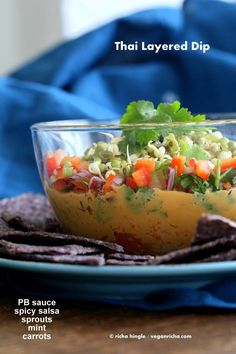 there is a bowl filled with vegetables and chips on the plate next to some tortilla chips