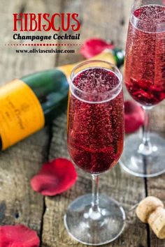 two wine glasses filled with champagne next to bottles and corks on a wooden table