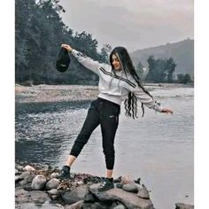 a woman is standing on rocks by the water