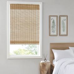 a bed sitting under a window next to a wooden headboard