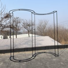 an artistic sculpture on top of a roof with trees in the background and snow covered ground