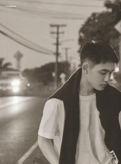 a young man standing on the side of a road