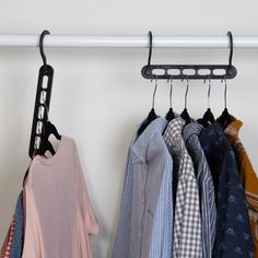 several shirts are hanging on a rail in front of a white wall and a coat rack