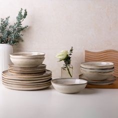 there are many bowls and vases on the table next to each other with flowers in them