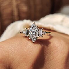 a woman's hand with a diamond ring on top of her finger and an engagement band