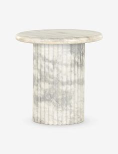 a round marble table with pleated white stripes on the top and bottom, standing against a gray background