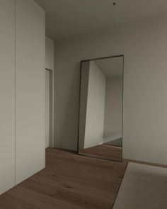 an empty room with a large mirror on the wall and wooden floors in front of it