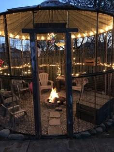 an outdoor fire pit surrounded by chairs and lights