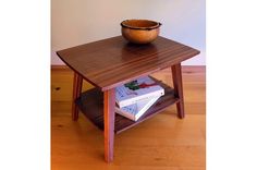 a wooden table with books on it and a bowl sitting on top of the table